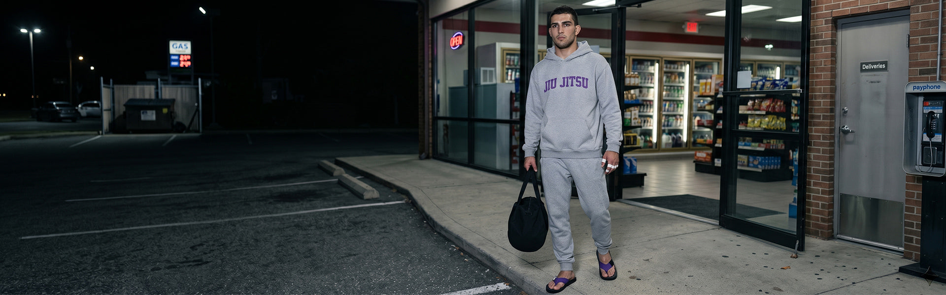 Adult BJJ practitioner wearing FlowFlip Jiu Jitsu apparel and purple belt flip flops outside at night